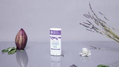 Schmidt's Natural Deodorant Lavender + Sage Stick on a purple background with lavender herbs